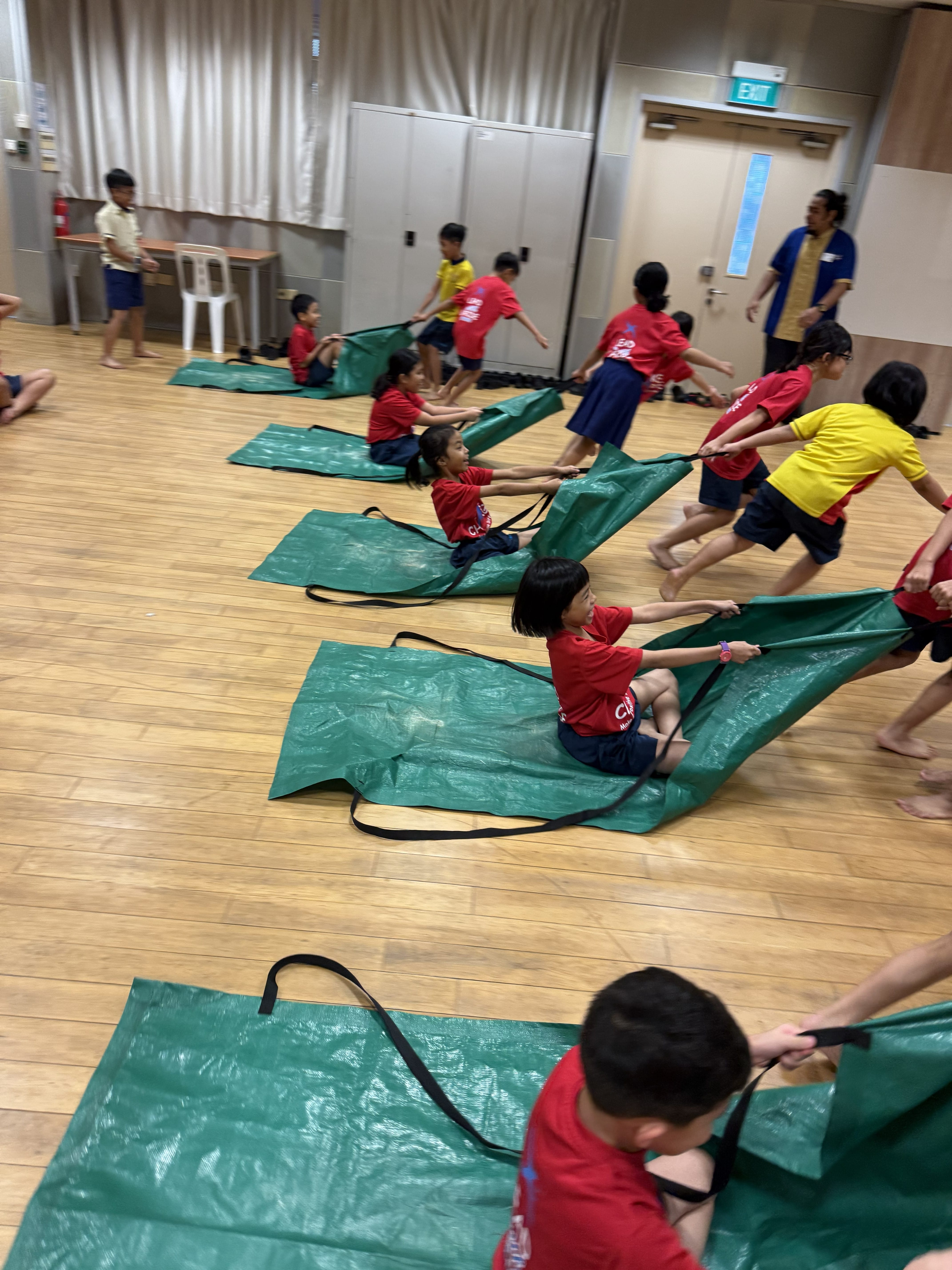 Students have fun working together with their friends to pull a sack with their friend seated on it